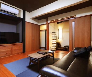 Living area with sofa, low table and tatami alcove at Toku no Yado Fubuan in Oita, Kyushu