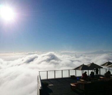 Sunlit terrace with umbrellas and loungers above a sea of clouds at Keikoku no Yu, Shiga Kogen, Nagano