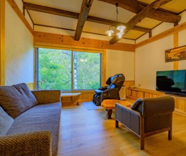 Wood-floored lounge with sofa, TV and massage chair at Keikoku no Yu, Shiga Kogen, Nagano, Japan