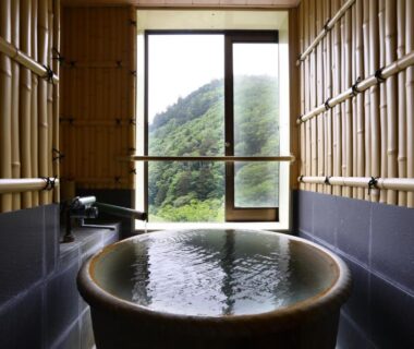 Round indoor onsen tub with bamboo walls overlooking forested valley at Keikoku no Yu Nagano
