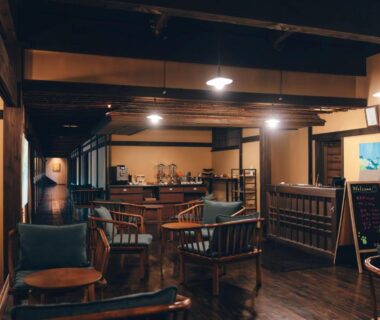 Warm wooden lounge with armchairs, low tables, exposed beams and reception area at Retraite Kominka in Gunma