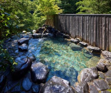 Outdoor rock-lined bath beside wooden fence at Retraite Kominka avec chien admis au mont Akagi, Gunma, Kantō