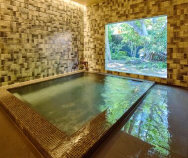 Tiled indoor soaking tubs beside large window overlooking a manicured garden at Retraite Kominka in Gunma