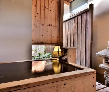 Wooden indoor bath with stone lantern and small garden view at Tamano-yu in Togura Kamiyamada Onsen