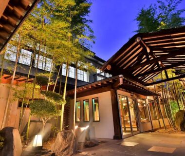 Illuminated bamboo-lined wooden entrance and pathway at Tamano-yu, Togura Kamiyamada Onsen, Nagano