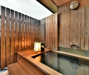 Wooden tub with lantern beside fenced open-air onsen at Tamano-yu, Togura Kamiyamada Onsen, Nagano