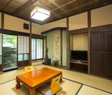 Traditional tatami room with low table, shoji screens, tokonoma alcove and garden view at Ōgi-sō in Kumamoto
