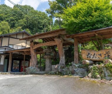 Timber gate and signboard at Ōgi-sō entrance surrounded by trees in Kumamoto, Kyūshū