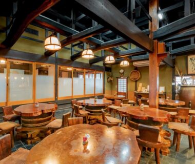 Traditional wooden dining room with round tables, exposed beams and frosted shoji partitions at Ryokan Isobe Kyoto