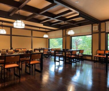 Dining room at Ryoan Kawaki in Nagano with wooden beams, polished floors and large windows framing trees