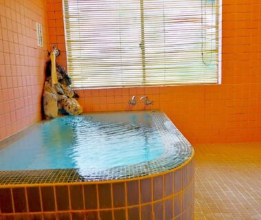 Tiled indoor bath with mosaic rim and window blinds at 旅館FURUYA in Nagano