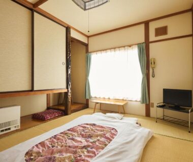 Tatami room with futon, sliding closet doors, low table and TV at Ryokan Ogita near Shiraoi Station, Hokkaidō