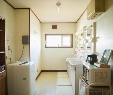 Shared laundry and wash area with washing machine and sinks at Ryokan Ogita near Shiraoi Station, Hokkaidō