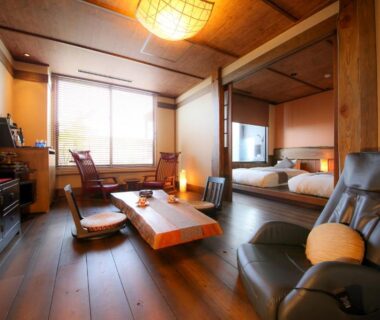 Spacious tatami room with low table, reclining chair, shoji screens and wooden flooring at 旅館かわな in Chiba