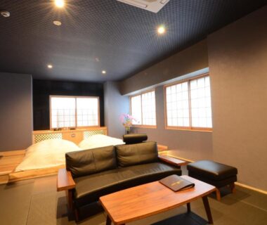 Tatami room with low sofa and raised sleeping area at Nihonryokan Utsuwa in Beppu Oita