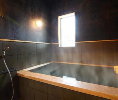 Indoor steaming wooden onsen bath with handheld shower at Nihonryokan Utsuwa in Beppu Oita