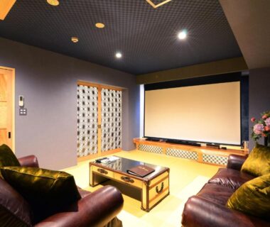 Seating area with leather sofas and projection screen in ryokan lounge in Beppu, Ōita