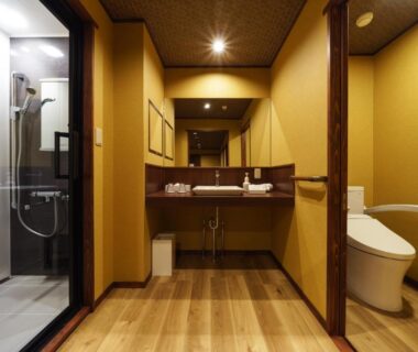 Bathroom with glass shower, sink and toilet at Hôtel Hisago-sō Tsukioka Onsen, Niigata