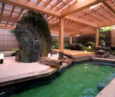 Covered onsen bath with wooden pergola and rock feature at Hôtel Hisago-sō, Tsukioka, Niigata