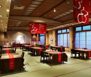 Tatami dining hall with low tables and red banners at Hôtel Hisago-sō, Tsukioka Onsen, Niigata, Chūbu, Japan