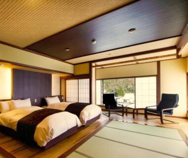 Tatami room with twin beds, shoji screens and seating area overlooking greenery at Hôtel Hisago-sō, Tsukioka Onsen, Niigata