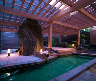 Onsen bath under wooden pergola with rock feature, lanterns and gravel at Hôtel Hisago-sō, Tsukioka Onsen