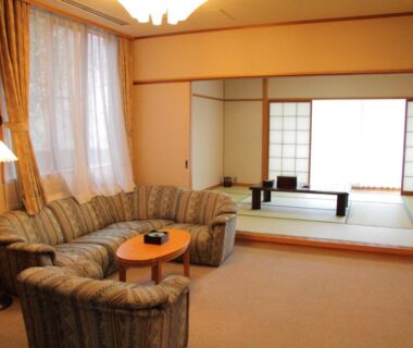 Carpeted lounge with sofa leading to tatami room with shoji screens and low table at Zuihōen Arima, Hyōgo