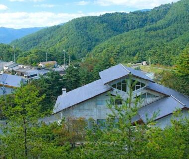 Aerial view of Matsutake Sansō buildings nestled in green forested hills of Nagano, Chūbu