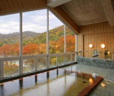 Spacious indoor onsen with large windows framing autumn mountains at Matsutake Sansō, Nagano