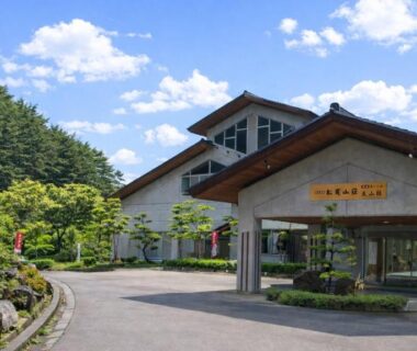 Driveway and landscaped garden leading to Matsutake Sansō entrance in Nagano with surrounding forested hills