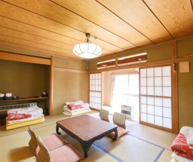 Traditional tatami room with low table, shoji screens and folded futons at Ryokan Kashiwaya, Nagano