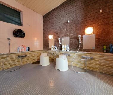 Shower stations with stools, mirrors and toiletries in a communal bathing area at Ryokan Kashiwaya, Nagano
