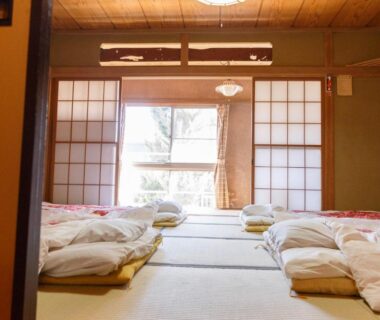 Tatami room with futons and shoji screens at Ryokan Kashiwaya share house in Nagano