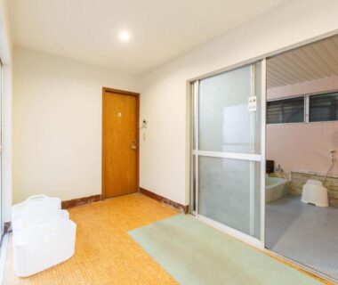 Sliding glass door leading to tiled bathing area with stools at Ryokan Kashiwaya, Nagano