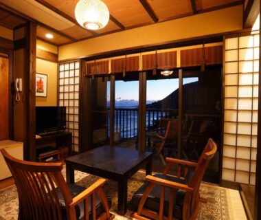 Traditional tatami room with low table, chairs, shoji screens and balcony framing distant landscape at dusk