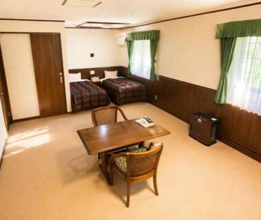 Spacious twin room with low wooden table, two beds, green curtains and wood-paneled walls at Morinouta in Tochigi