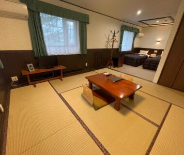 Spacious tatami mat room with low table and adjacent Western bed area at Morinouta in Nikko, Tochigi