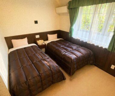 Bright twin bedroom with two single beds, wooden headboard, bedside table and window at Morinouta in Nikko, Tochigi