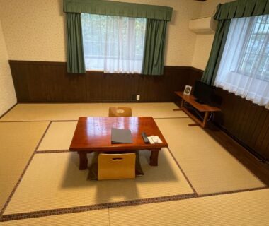 Tatami room with low table, cushions and curtained windows at 森のうた Morinouta in Nikko, Tochigi