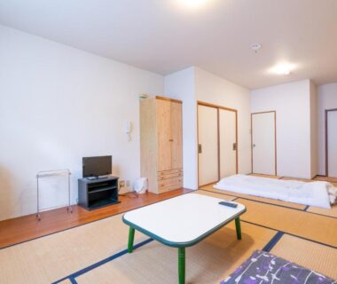 Bright tatami room with futon bedding, low table, TV and sliding doors at Kitakaruizawa Kogen Hotel in Gunma