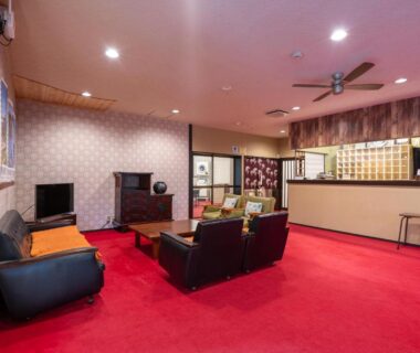 Spacious ryokan lobby with red carpet, sofas, reception counter and wooden key boxes at Kitakaruizawa Kogen Hotel in Gunma