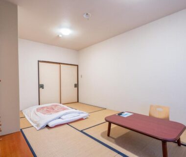 Tatami room with folded futon and low table at Kitakaruizawa Kogen Hotel in Gunma