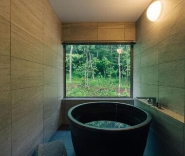 Round wooden bathtub in tiled room with large window overlooking forest at 森のオーベルジュ 三 みつ Hokkaidō
