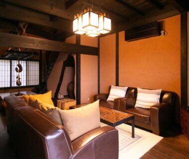 Leather sofas and shoji screens in Musōan Biwa lounge with warm wooden beams in Shizuoka ryokan