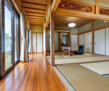 Large tatami room with wooden floor, shoji screens and garden-facing windows at Rakushinkan in Yufuin, Ōita