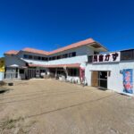Two-story Minshuku Kazu exterior with banners and gravel courtyard under clear blue sky, Chiba Kantō
