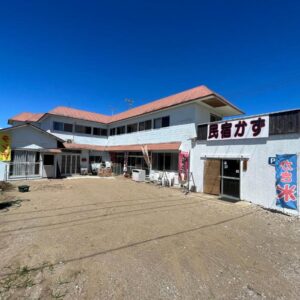 Two-story Minshuku Kazu exterior with banners and gravel courtyard under clear blue sky, Chiba Kantō