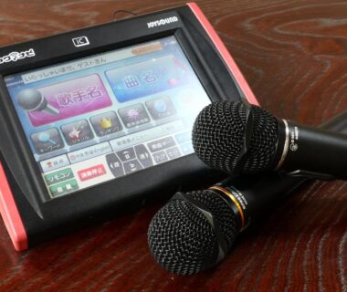 Touchscreen karaoke console with two microphones on a wooden table at Minshuku Kazu, Chiba, Kantō