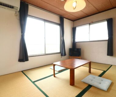 Tatami room with low table and floor cushion, windows with curtains at Minshuku Kazu, Chiba