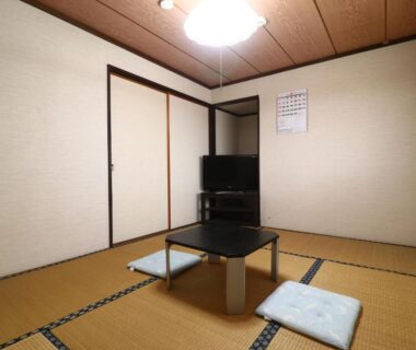 Simple tatami room with low table, floor cushions, sliding fusuma doors and television at Minshuku Kazu in Chiba, Kantō